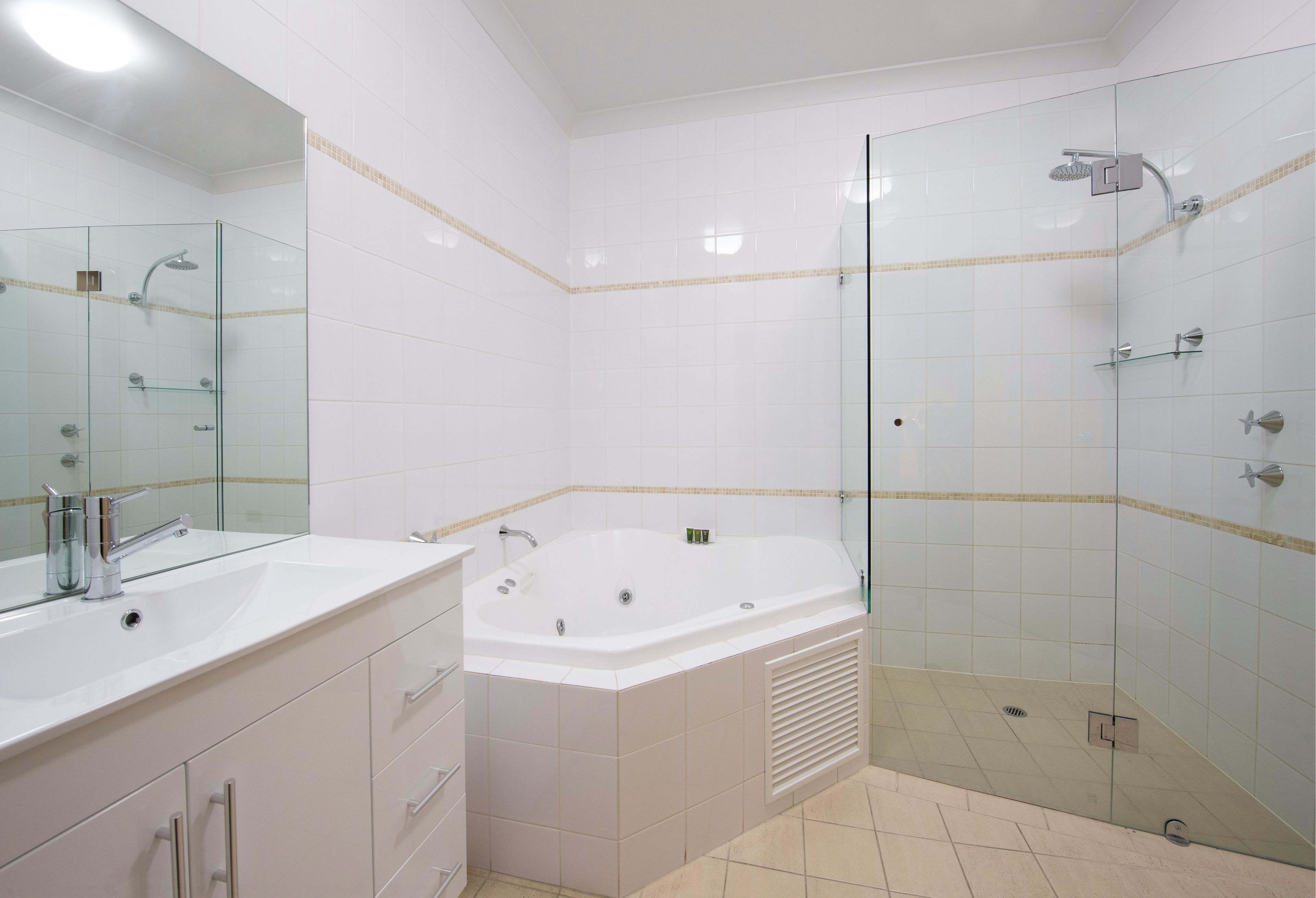A modern bathroom with a glass-enclosed shower, a large bathtub, and a vanity with a mirror.