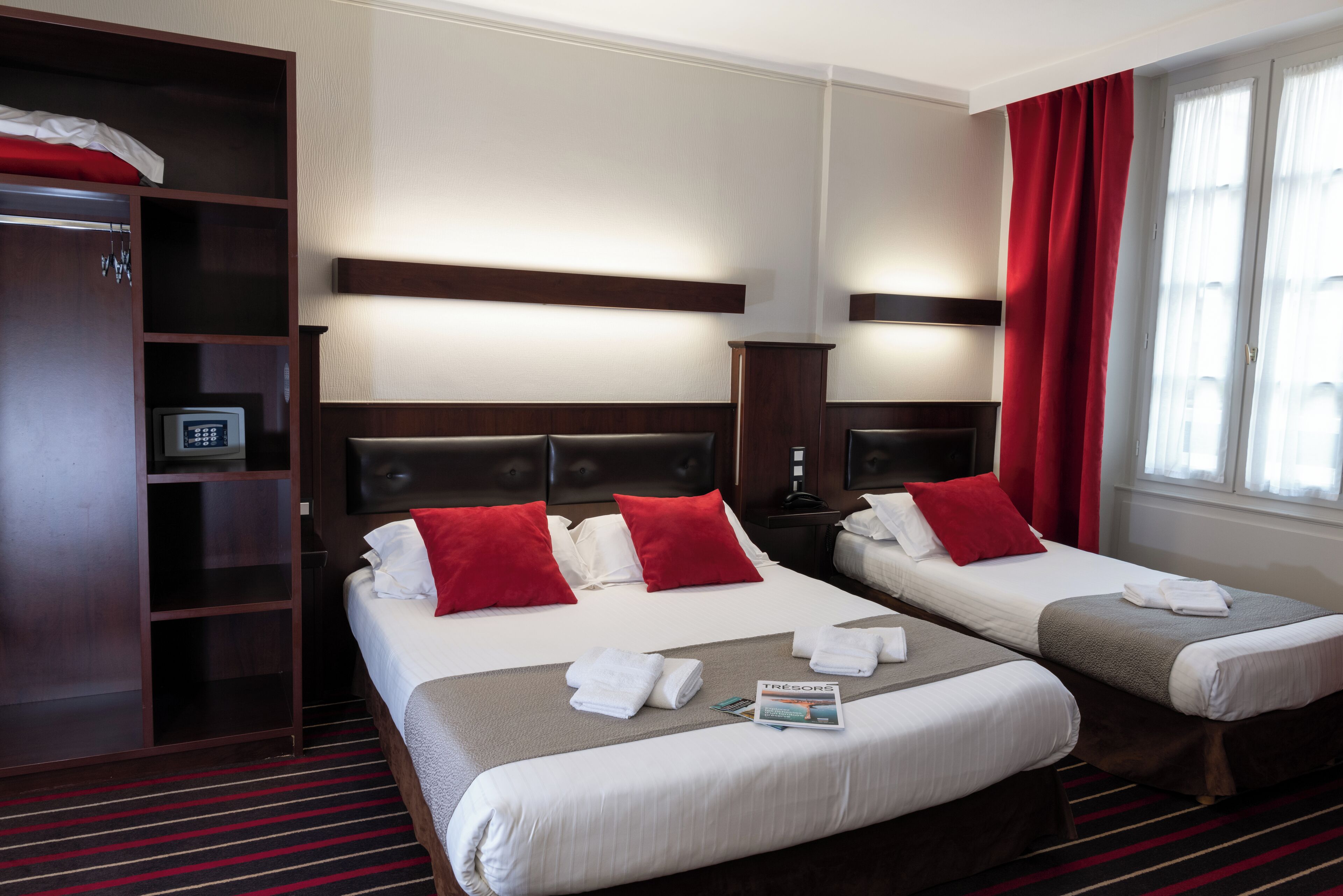 A hotel room with two beds, a wardrobe, and a nightstand.