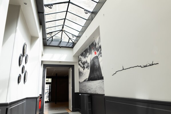 Interior moderno com claraboia, um mural de um farol e uma fotografia em preto e branco na parede.