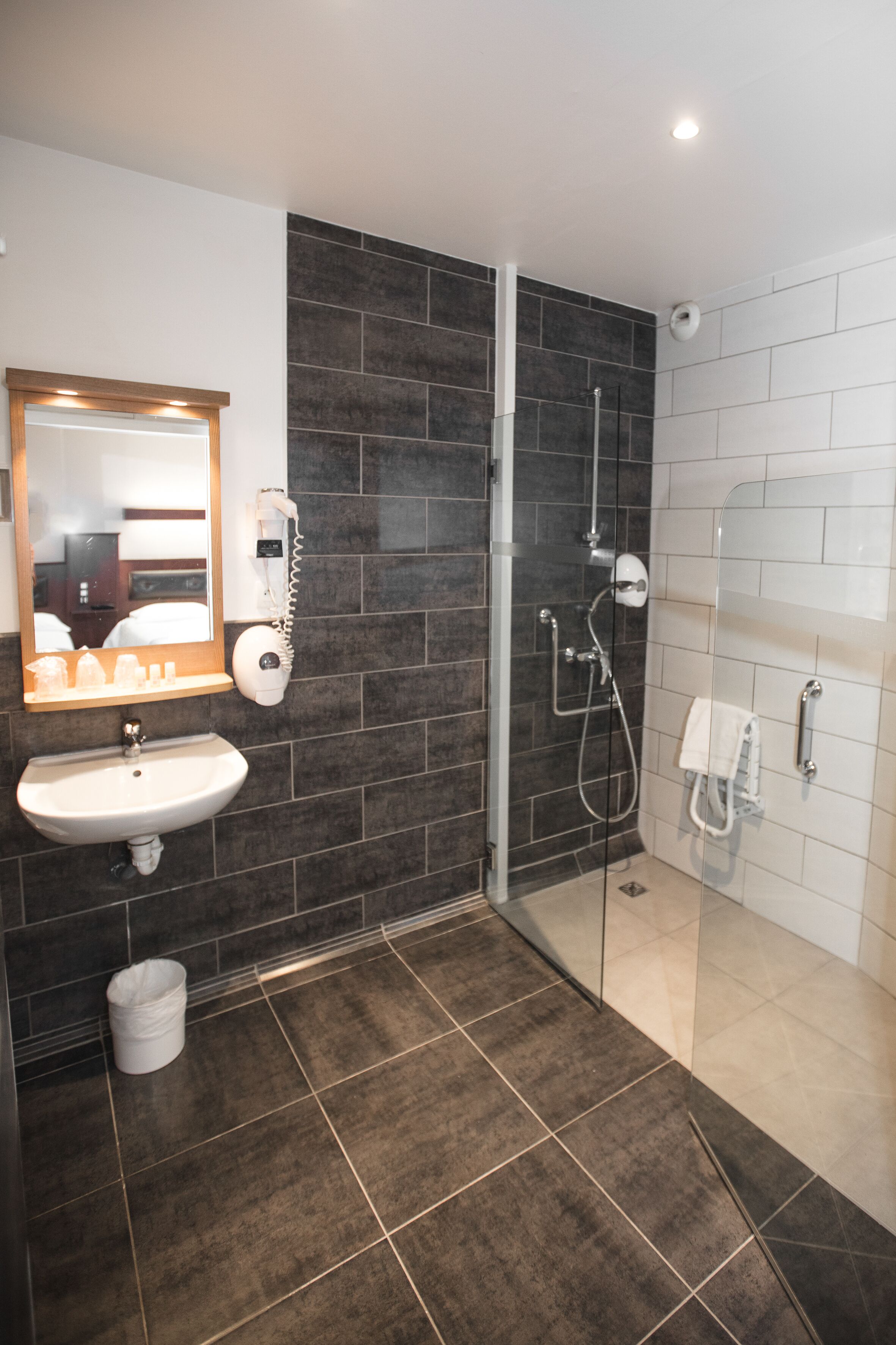 A modern bathroom with a glass shower enclosure, a sink, and a mirror.