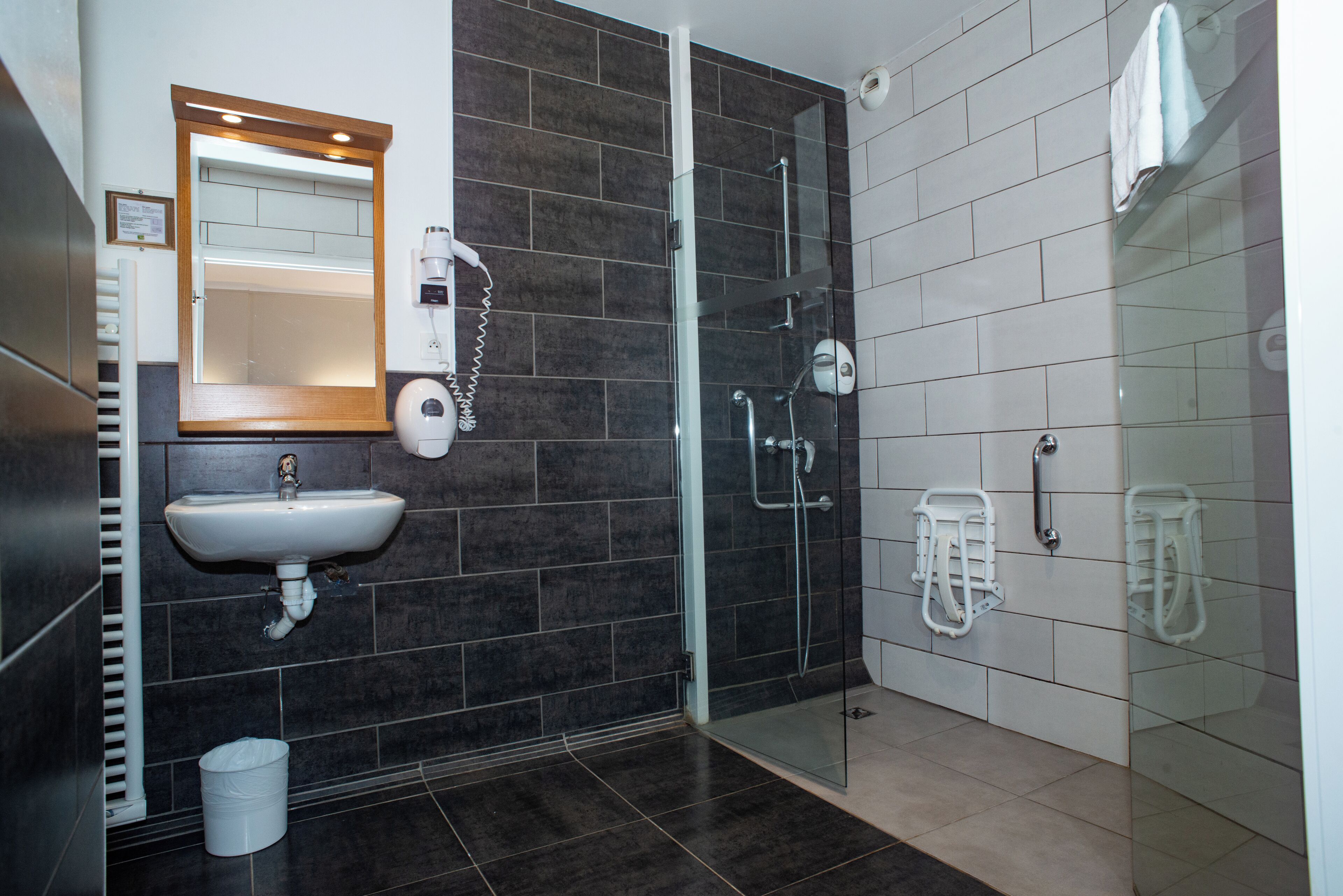 A modern bathroom with a glass shower enclosure, a white sink, and a mirror with a wooden frame.