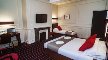 Hotelkamer met een groot bed, een kleiner bed, een bureau met een computer, een stoel en een open haard.