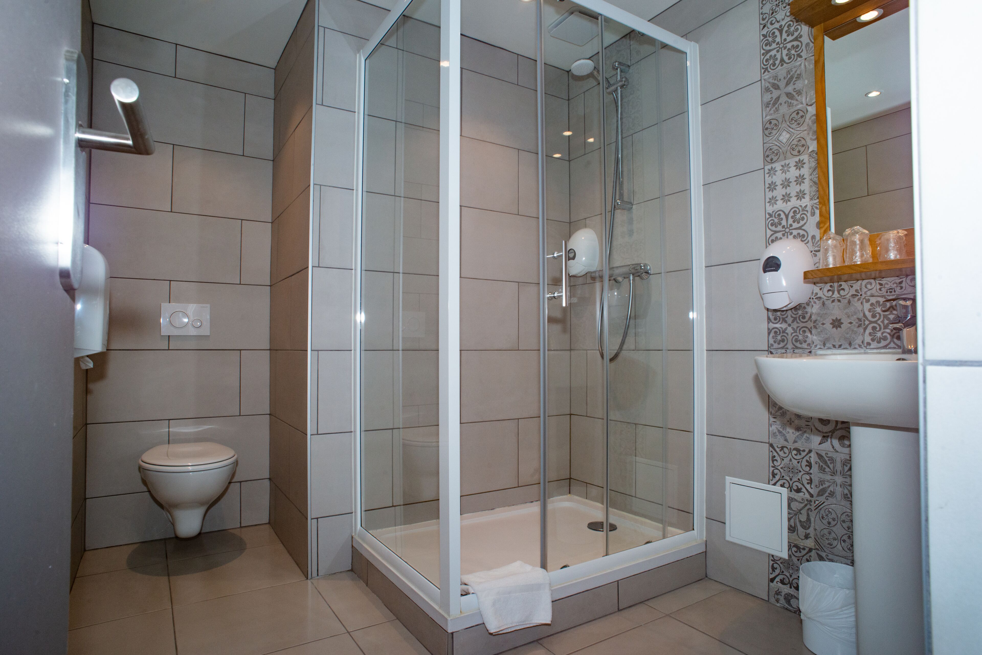 A modern bathroom with a glass-enclosed shower, a toilet, and a sink with a mirror above it.