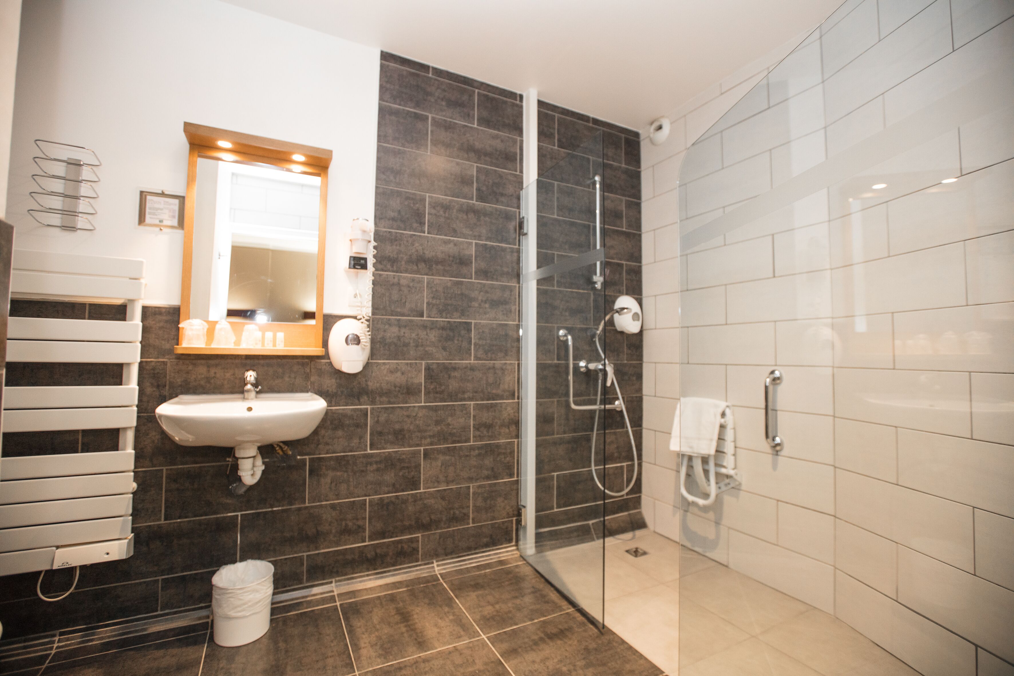 A modern bathroom with a glass shower enclosure, a sink, and a towel rack.