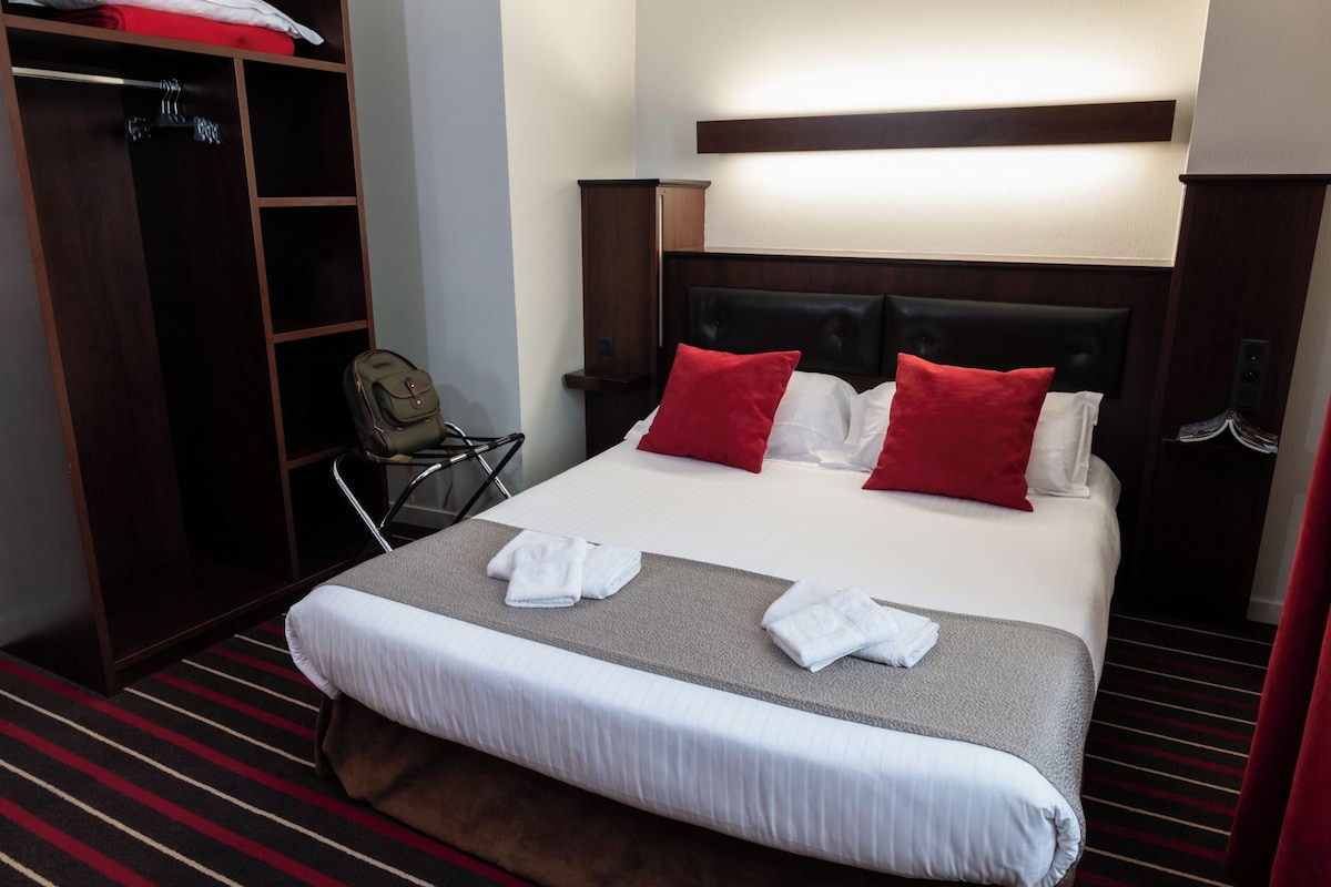 Una habitación de hotel con una cama bien hecha, un armario y una silla.