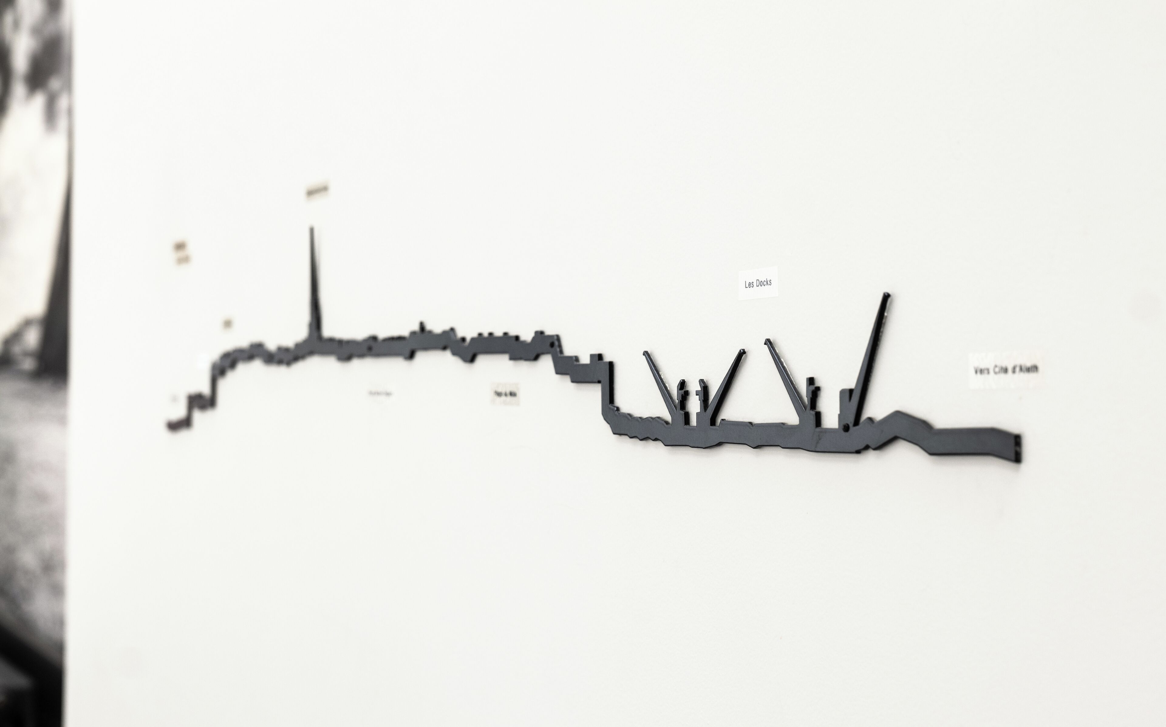 Dibujo en blanco y negro de un muelle con barcos, con la etiqueta 'Les Docks' y 'Vers Cité d'Art'.