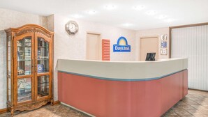 Een receptiebalie met een Days Inn logo, een houten displaykast en een klok aan de muur.