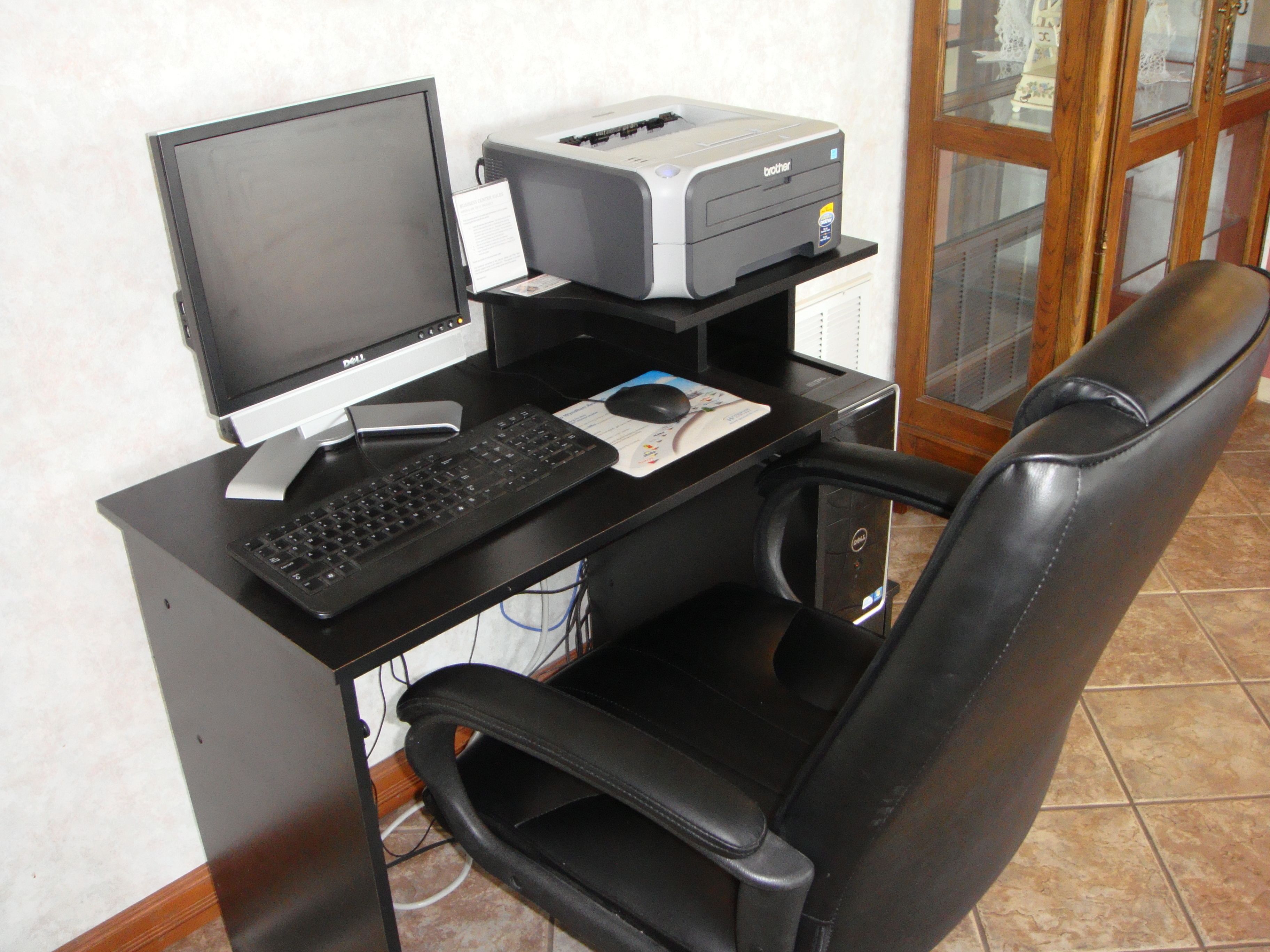 A computer desk with a monitor, keyboard, mouse, and printer.