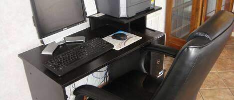 A computer desk with a monitor, keyboard, mouse, and printer.