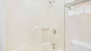 Een badkamer met een bad, douche en toilet.