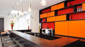 A modern kitchen with a central island, bar stools, and a red and black color scheme. - Residhome Appart Hotel Nancy Lorraine (Nancy)