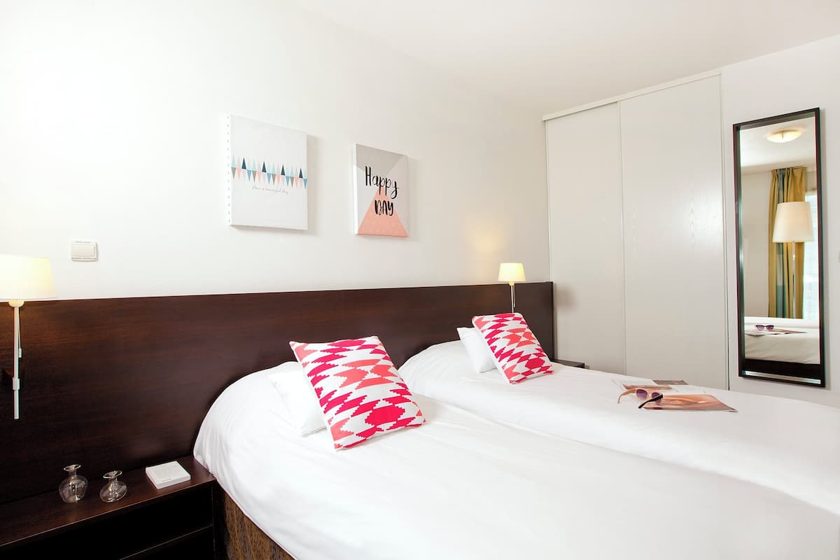 Een hotelkamer met een groot bed, twee nachtkastjes, een spiegel en twee aan de muur hangende foto's.