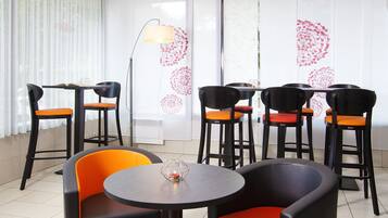 A modern dining area with black and orange chairs, a round table, and a floor lamp.