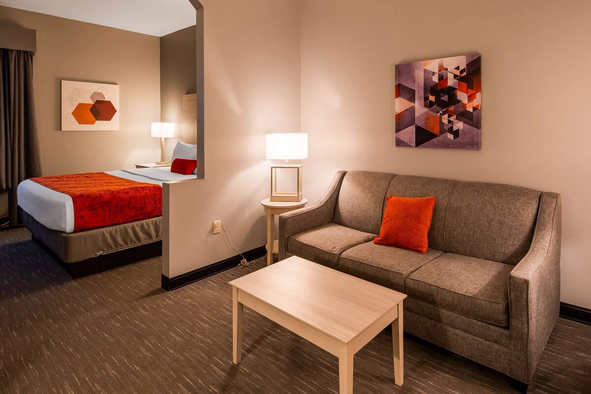 Een hotelkamer met een bed, een bank, een bijzettafeltje en twee lampen.