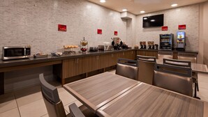 Una cocina moderna con microondas, tostadora y cafetera. Hay letreros que indican 'Fulfill Grains & Dairy' y 'Delight Juice Bar'.