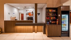 Un área de recepción con un mostrador de madera, una máquina expendedora y un estante para refrigerios.