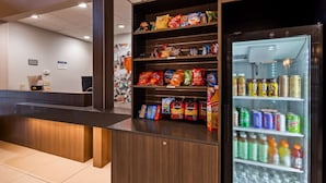 Zona de recepción con mostrador, estanterías para aperitivos y nevera para bebidas.