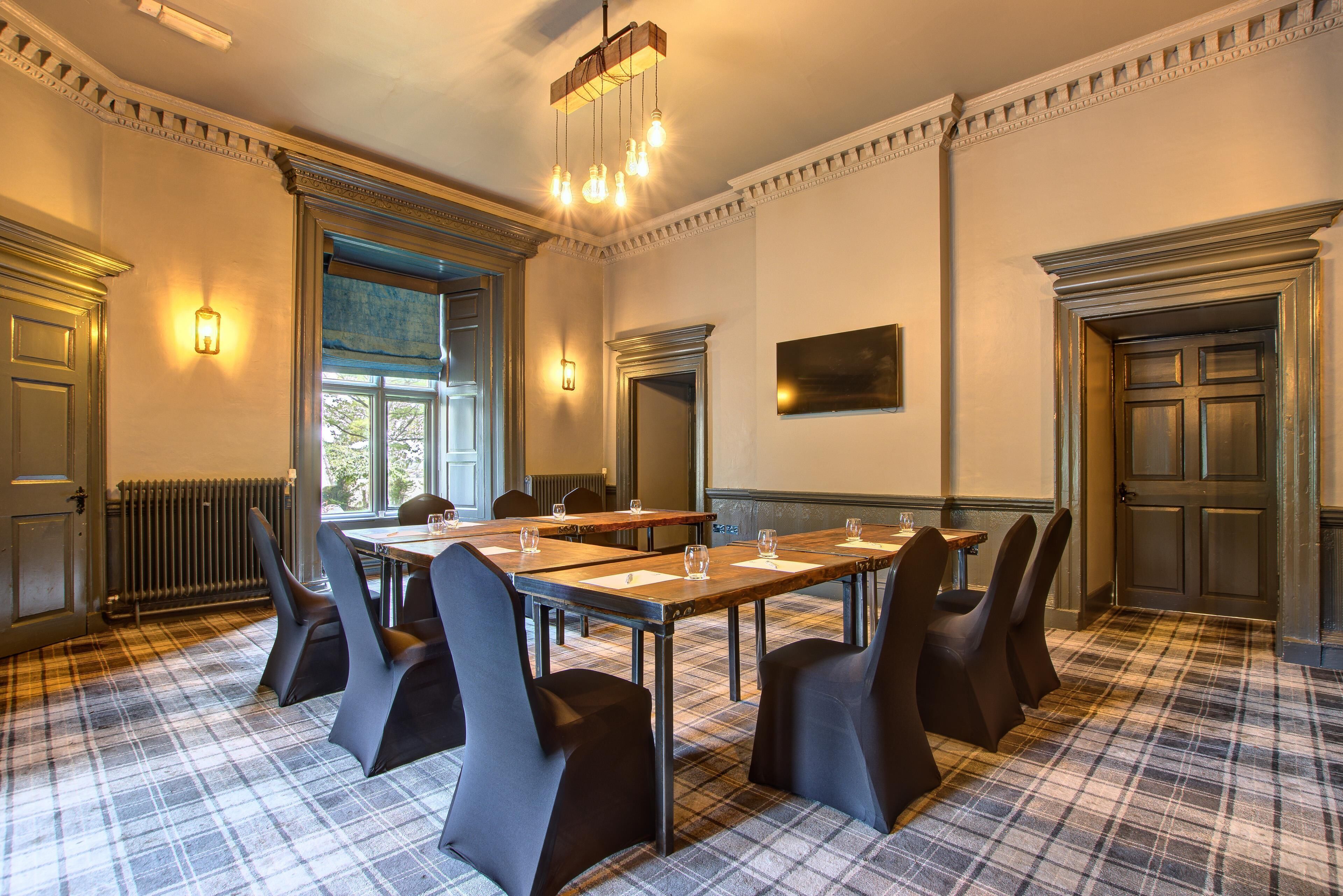 Une salle de conférence avec une longue table, des chaises et un lustre.