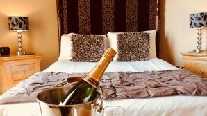 A hotel room with a bed, a bedside table with a lamp, and a bottle of champagne in a bucket. - Walworth Castle Hotel, BW Signature Collection (Darlington)