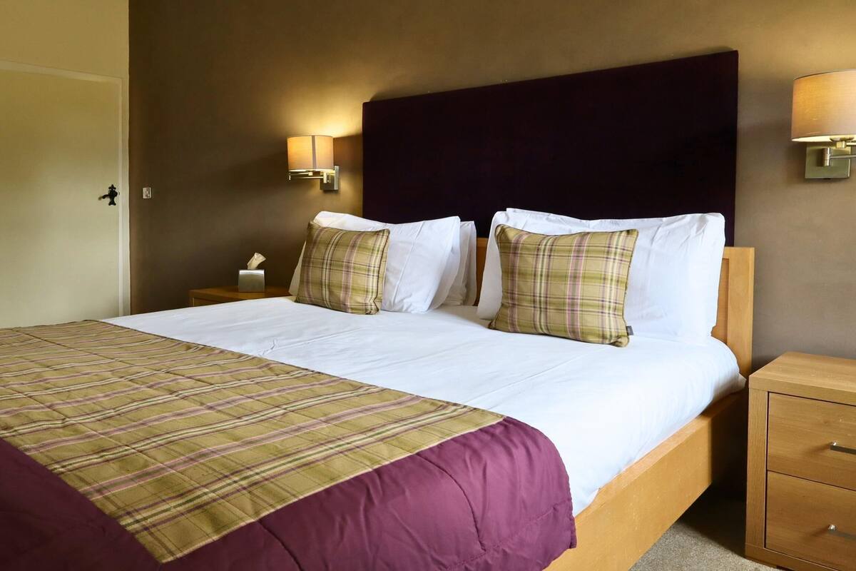 Una habitación de hotel con una cama grande, dos mesitas de noche y una puerta.