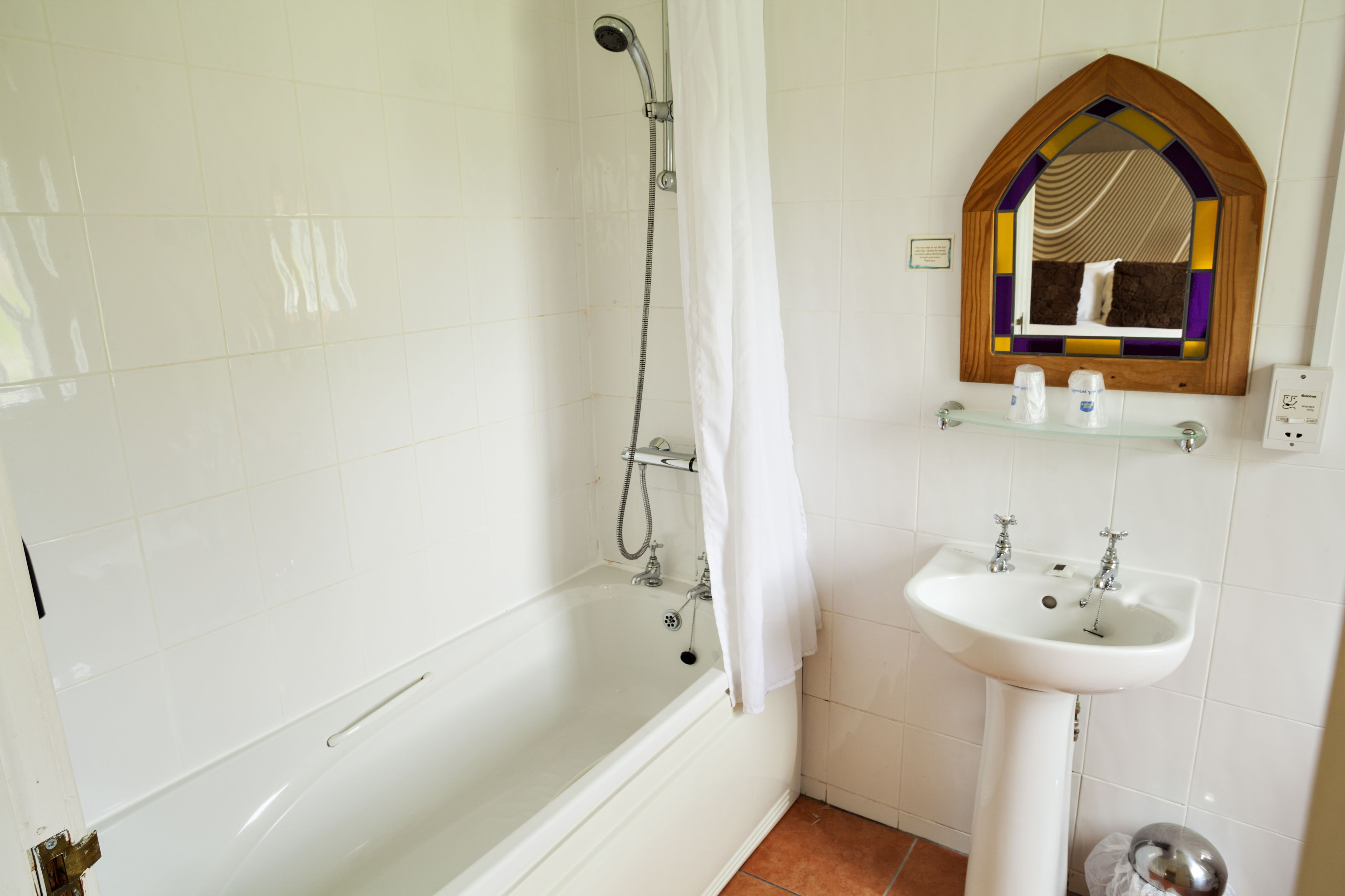 Un baño con una bañera blanca, ducha y lavamanos con espejo.