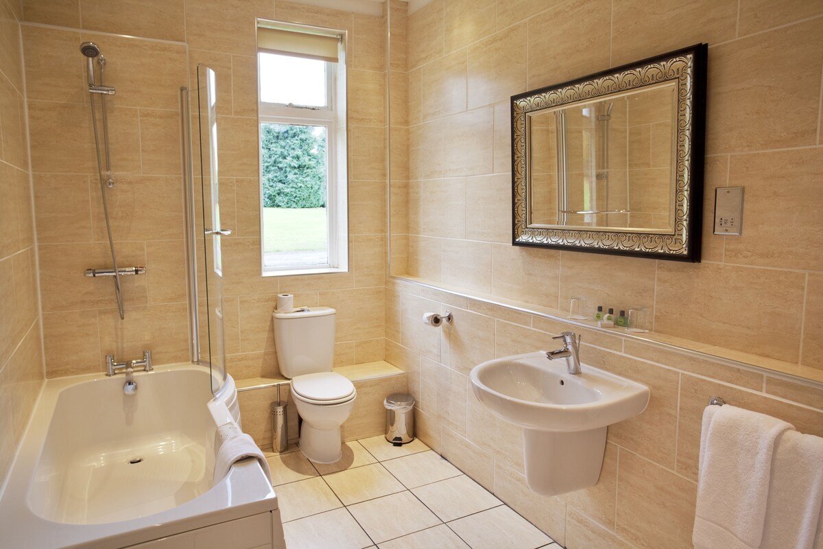 A bathroom with a bathtub, toilet, sink, and a large mirror.