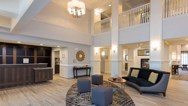 A spacious lobby with a reception desk, seating area, and a staircase to an upper level.
