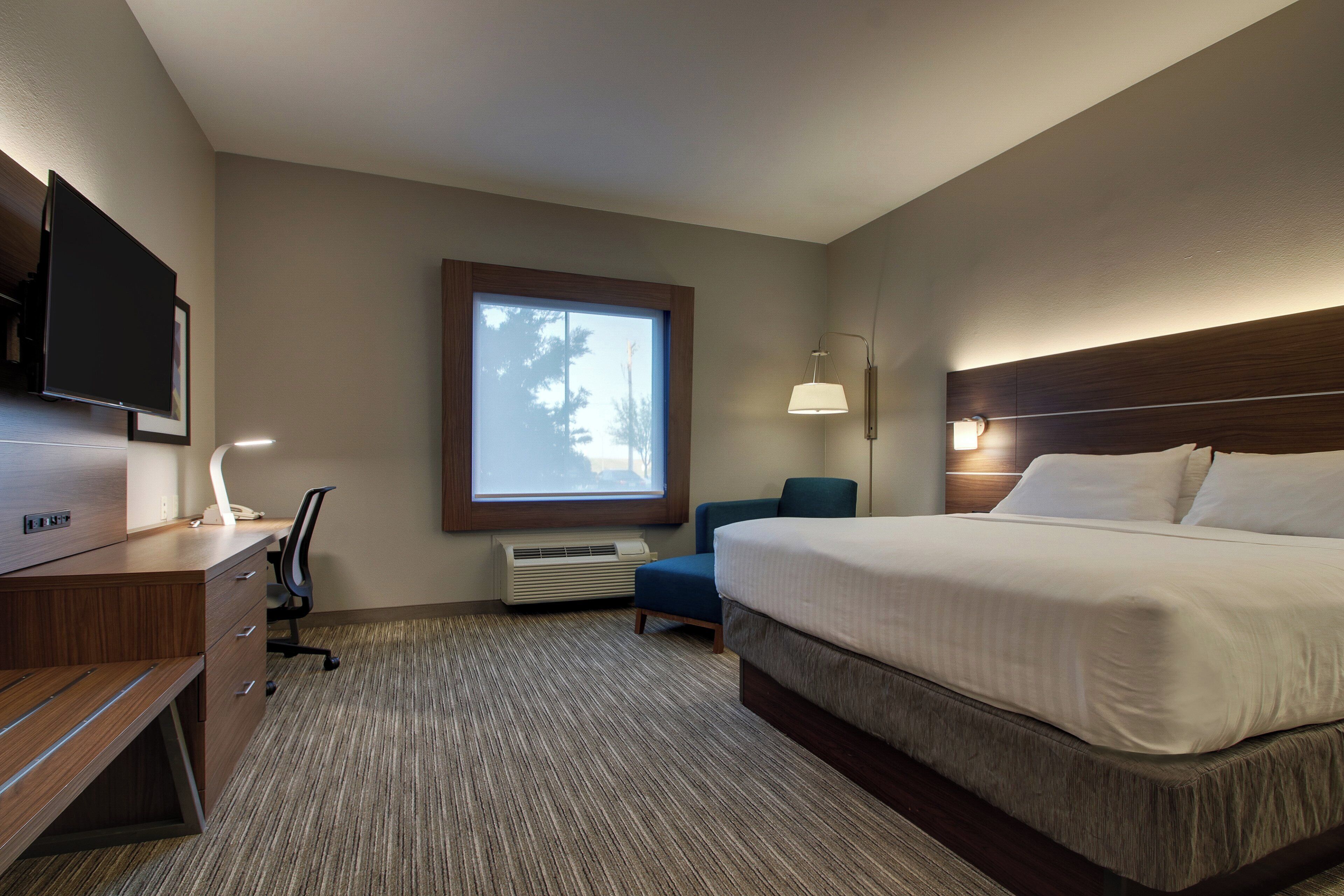 A hotel room with a bed, desk, chair, TV, and window.