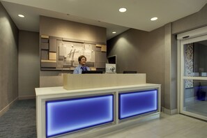 A hotel reception desk with a modern design, a digital display, and a glass door entrance. - Holiday Inn Express Hotel & Suites Vernon College Area by IHG (Vernon)