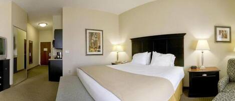 Una habitación de hotel con una cama grande, dos mesitas de noche con lámparas, una silla, un escritorio con computadora y un televisor.