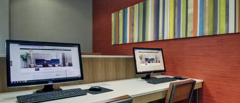 Een moderne kantoorruimte met twee bureaureecomputers, een houten bureau en een kleurrijke gestreepte wand.