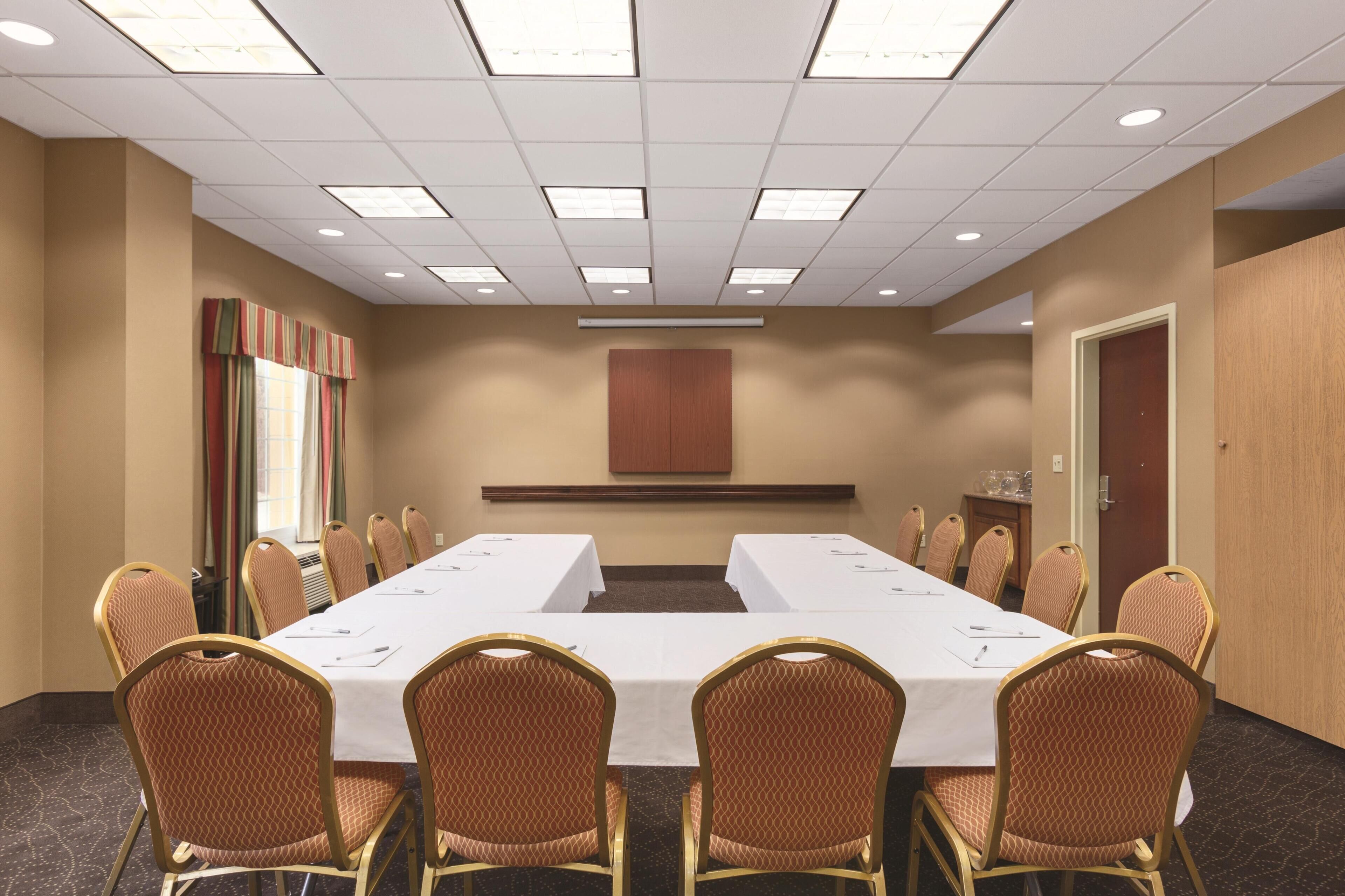 A conference room with a long table, chairs, and a neutral color scheme.