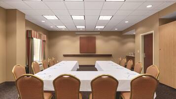 A conference room with a long table, chairs, and a neutral color scheme.