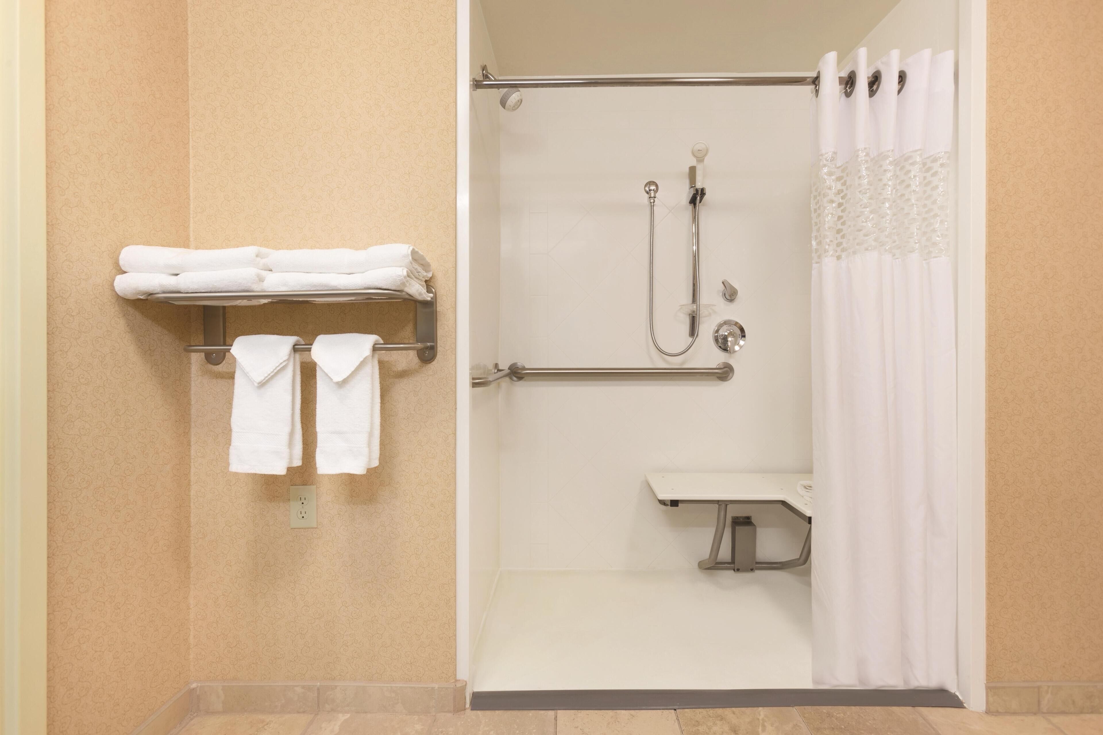 A shower with a handheld showerhead, a handheld showerhead, and a handheld showerhead.