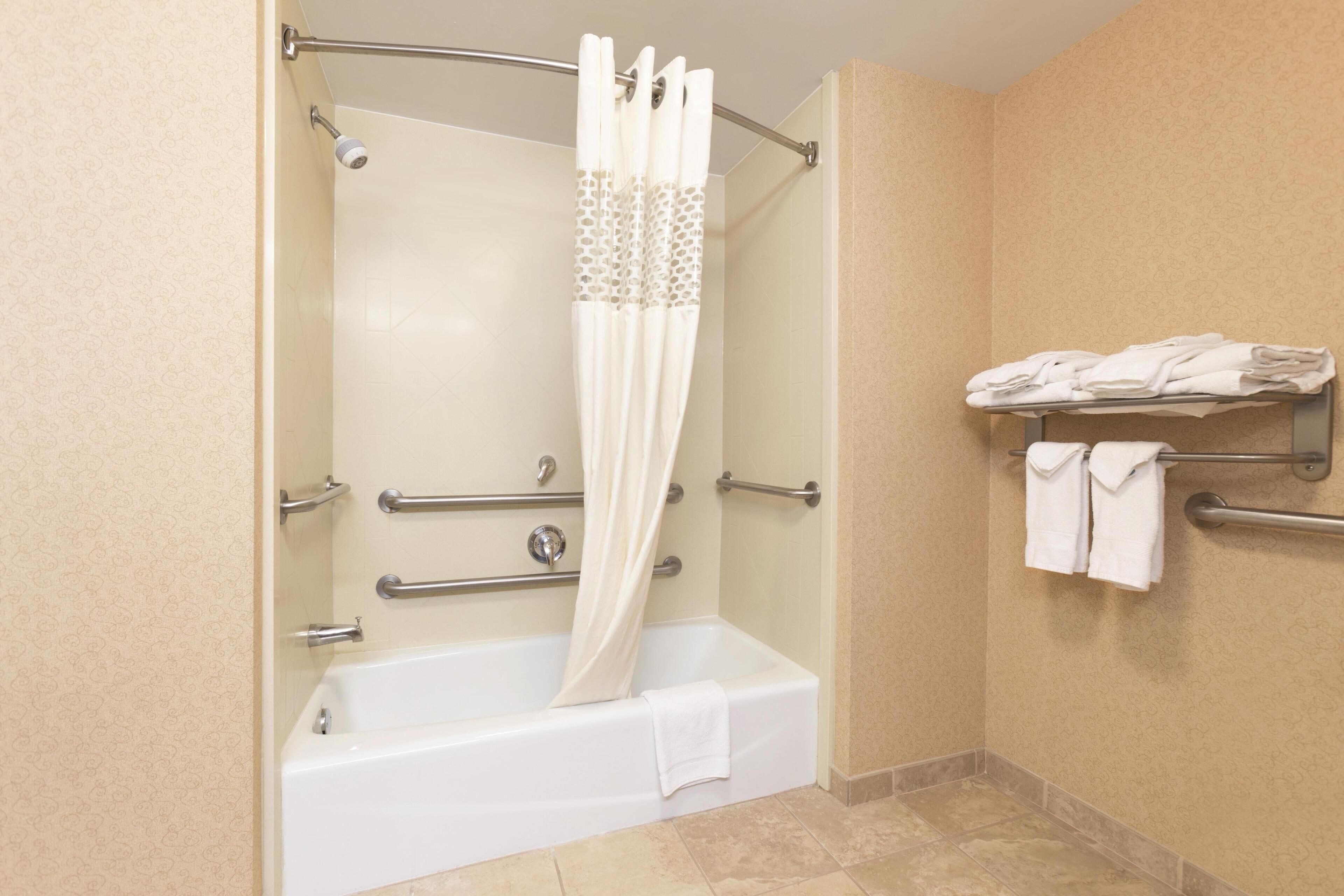 Une salle de bain équipée d’une baignoire, d’un rideau de douche, d’un porte-serviettes et de toilettes.