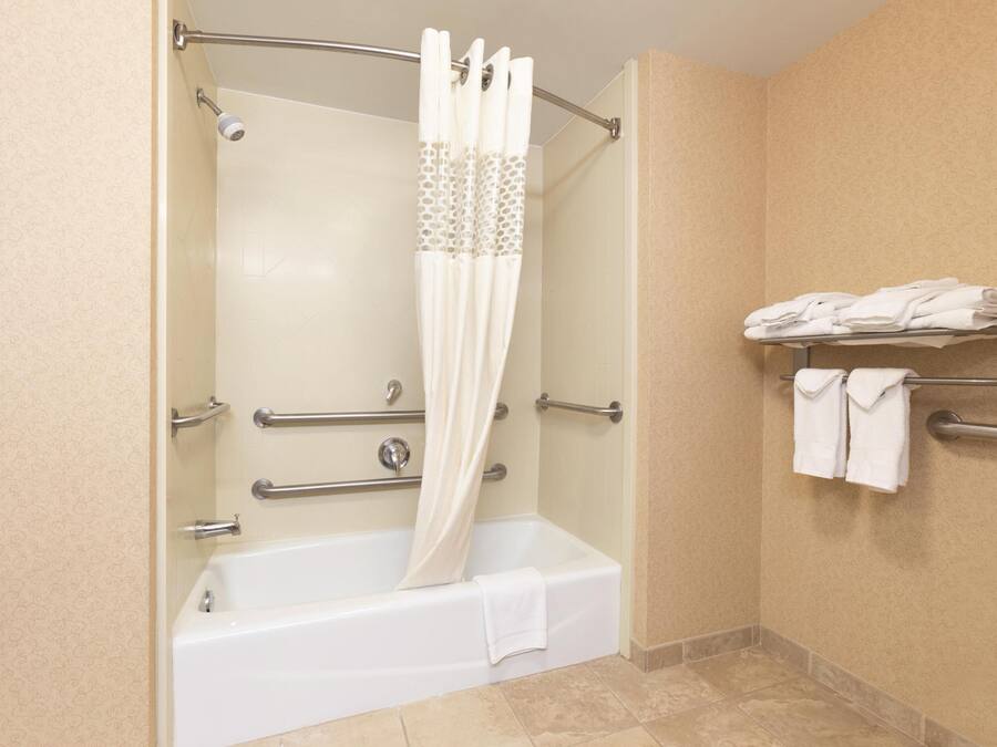 A bathroom with a bathtub, a shower curtain, a towel rack, and a toilet.