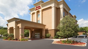 A hotel with a large entrance, a sign reading 'Hampton Inn & Suites,' and a parking lot.
