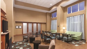 A hotel lobby with a fireplace, seating area, and large windows.