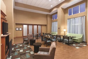 Un hall de hotel con chimenea, zona de estar y grandes ventanales.