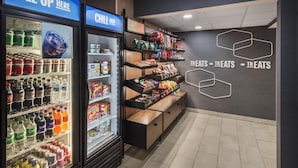 A beverage cooler with various drinks, a snack display, and a wall with 'TREATS' signage.
