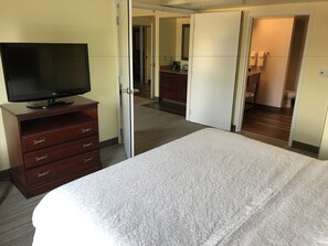 A hotel room with a bed, a TV on a wooden dresser, and a bathroom visible through an open door. - Hampton Inn & Suites Lamar (Mill Hall)