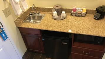 Una cocina con encimera de granito, pileta de acero inoxidable y cafetera.