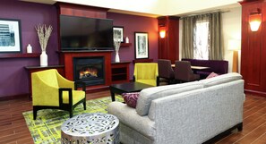 A living room with a fireplace, a television, and seating arrangements. - Hampton Inn & Suites Lamar (Mill Hall)