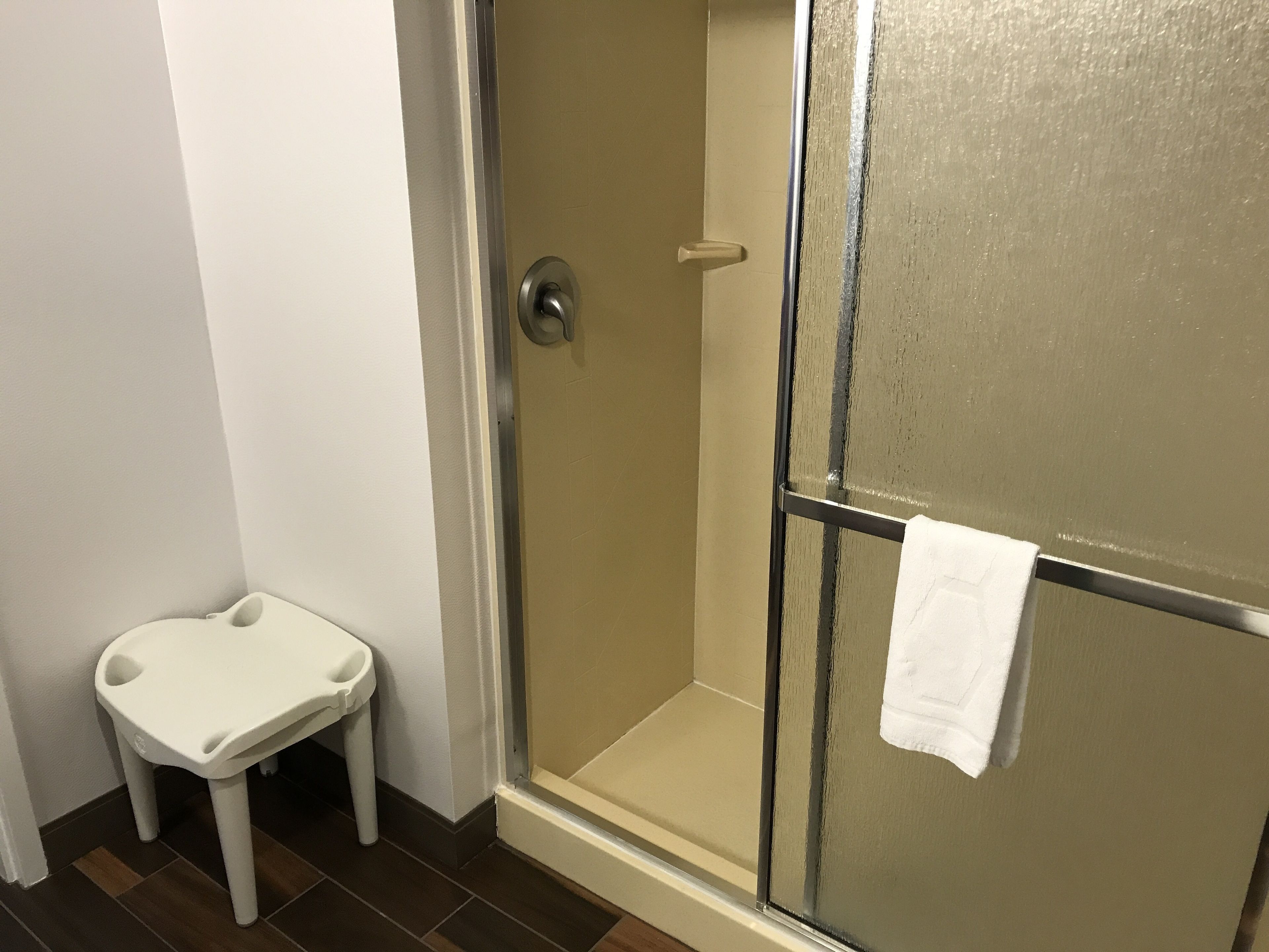 Un baño con ducha, un lavamanos blanco y un perchero para toallas.