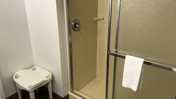 Un baño con ducha, un lavamanos blanco y un perchero para toallas.