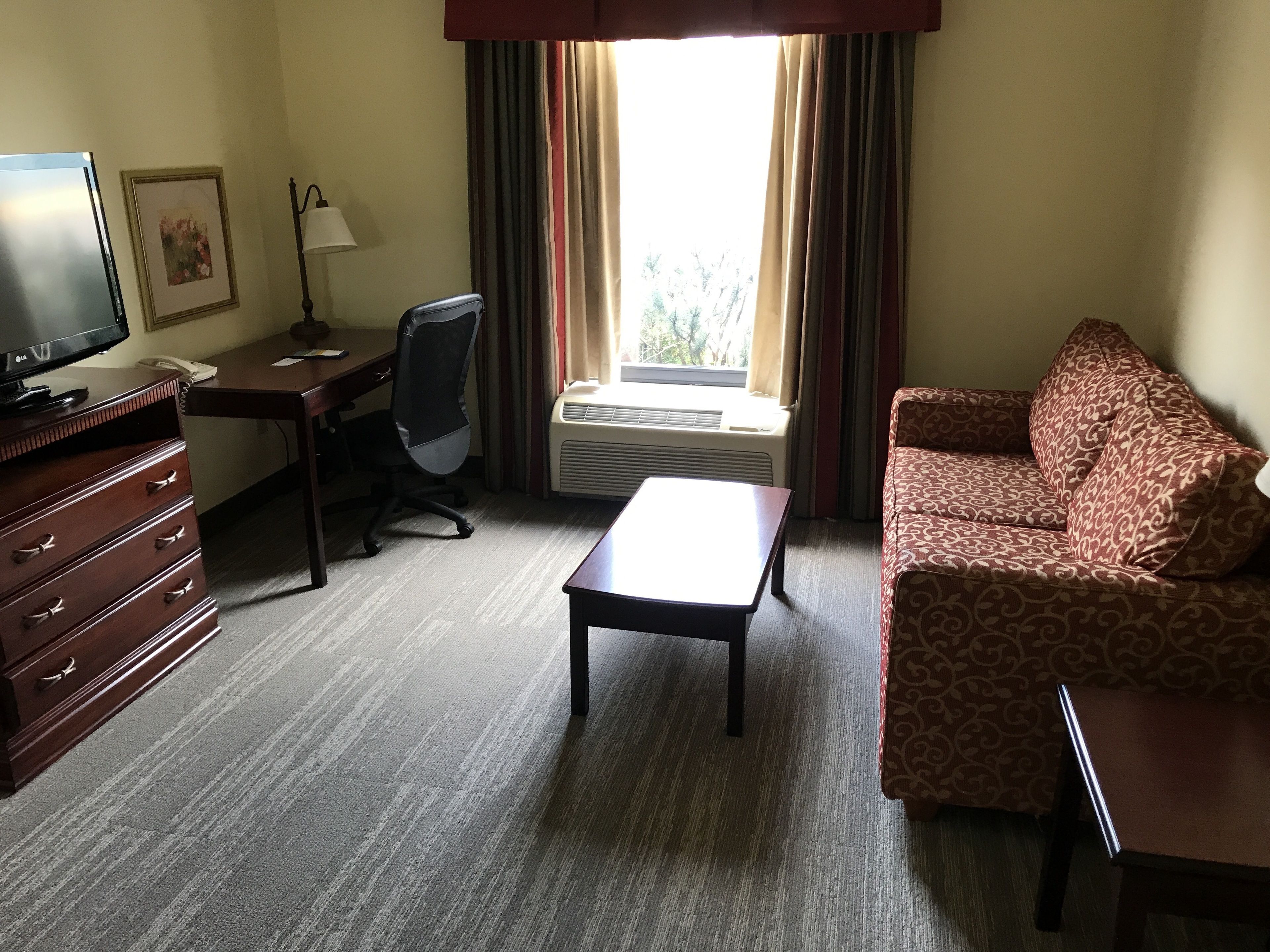 Una habitación de hotel con escritorio, silla, sofá y televisor.