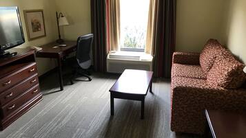 Una habitación de hotel con escritorio, silla, sofá y televisor.
