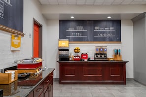 A breakfast bar with juice dispensers, a coffee machine, and a chalkboard menu.