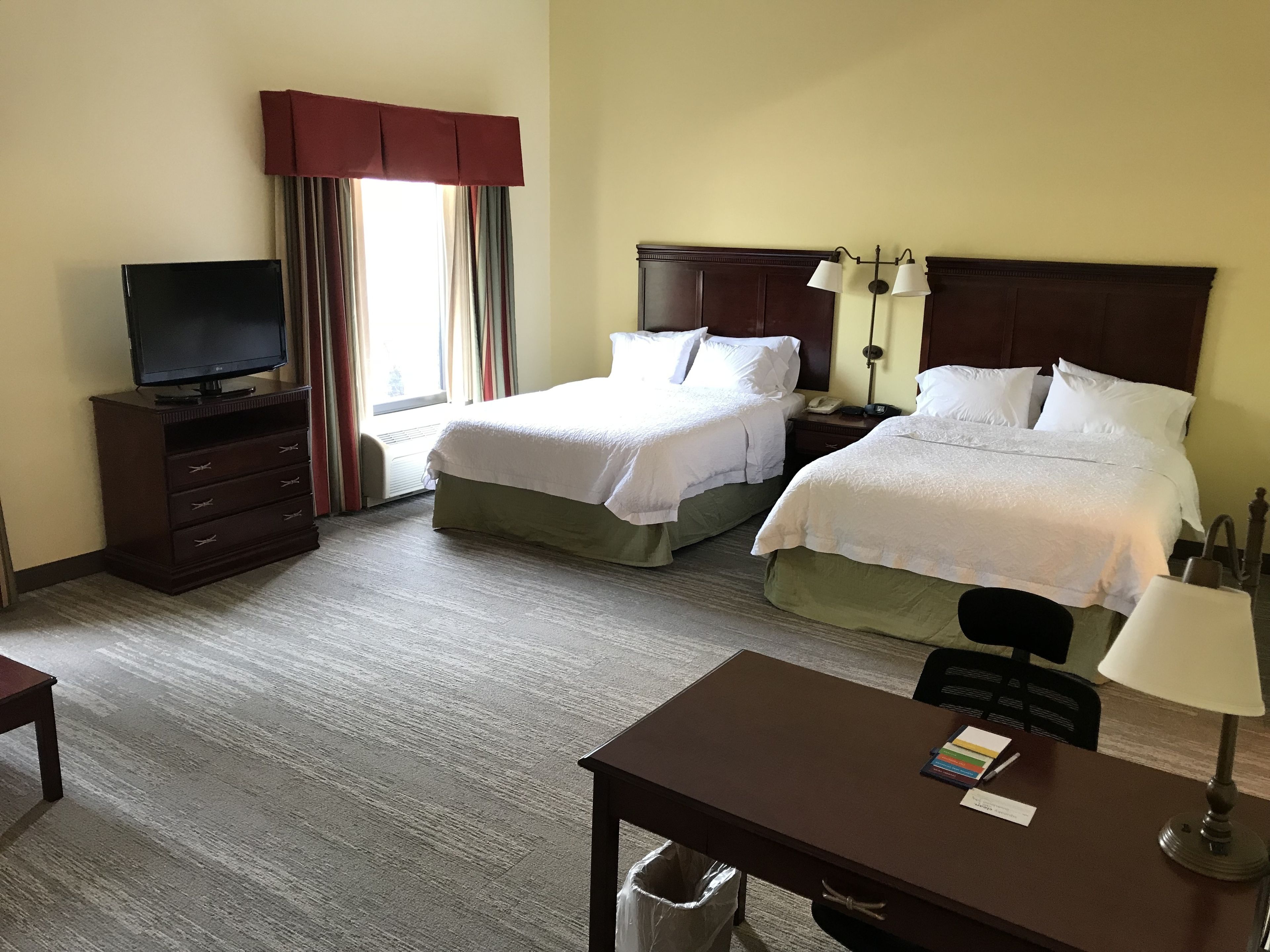 Une chambre d’hôtel avec deux lits, un bureau, une télévision et une lampe.