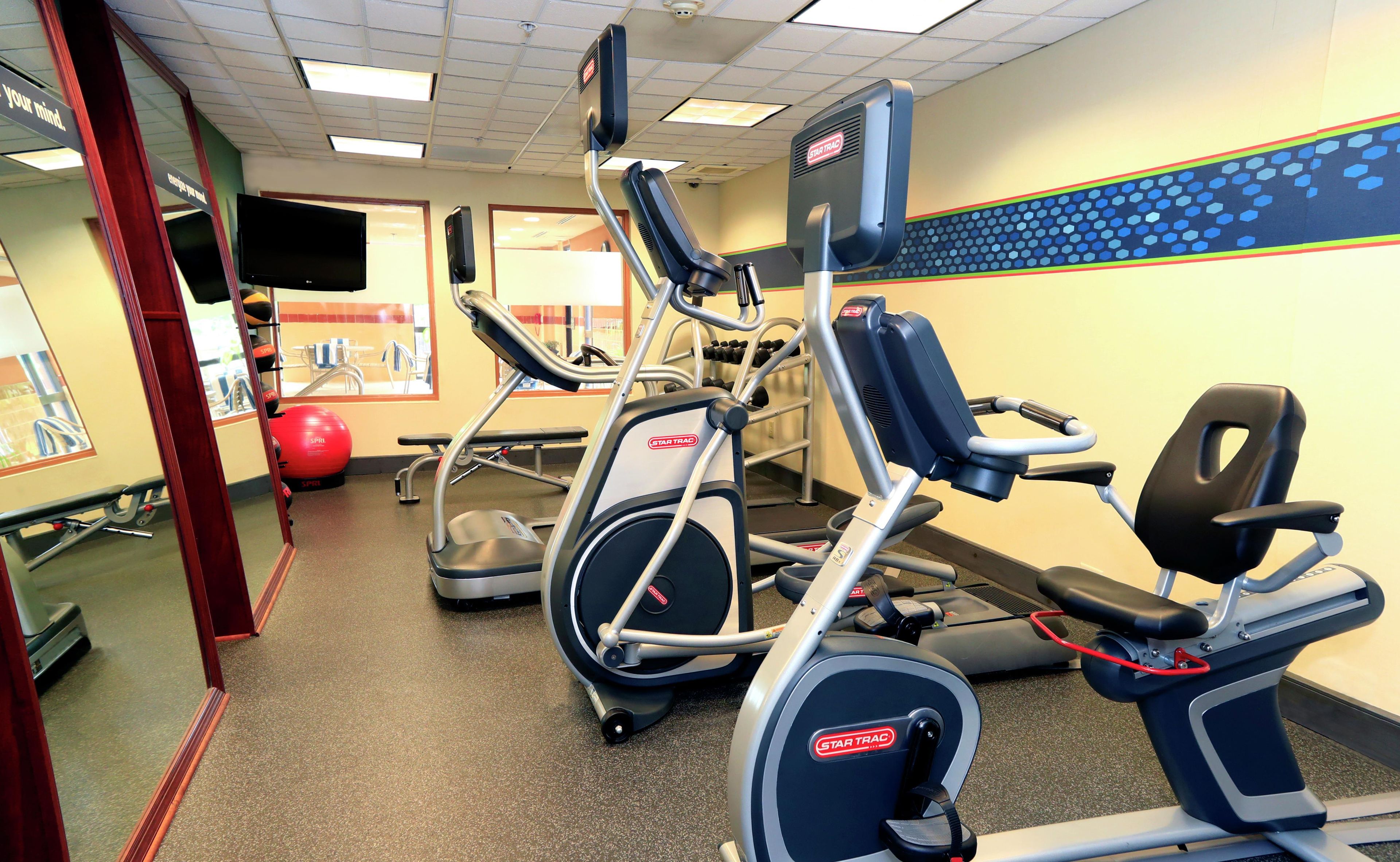 A gym with various exercise equipment including treadmills and elliptical machines.
